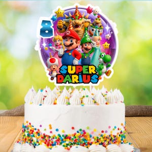 Puede incluir: Un pastel glaseado blanco con chispas de colores y remolinos de glaseado blanco. El pastel est&aacute; cubierto con un adorno para pastel con el tema de Super Mario con el n&uacute;mero 8 y el nombre "Darius". El adorno para pastel presenta a Mario, Luigi y otros personajes.