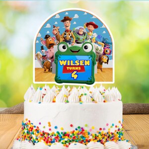 May include: A white frosted cake decorated with colorful sprinkles and white frosting swirls. The cake is topped with a decorative sign featuring characters from Toy Story and the text "Wilsen Turns 4".
