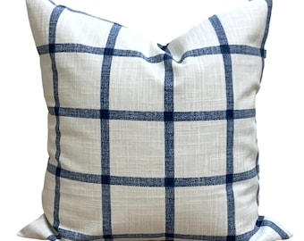 Könnte beinhalten: Quadratisches Zierkissen mit weißem Hintergrund und einem marineblauen Karomuster. Das Kissen hat ein strukturiertes Aussehen und ist für den dekorativen Einsatz auf einem Bett oder Sofa konzipiert.
