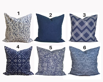 May include: Six decorative throw pillows in various blue and white patterns. Designs include geometric, abstract, and solid textures. The pillows are square-shaped and rest on a white background, offering a range of styles for home decor.