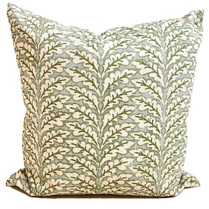 May include: A square throw pillow featuring a repeating vertical pattern of dark green oak leaves on a light sage green background. The fabric has a visible woven texture, and the pillow is filled to create a plump, soft, and structured shape.