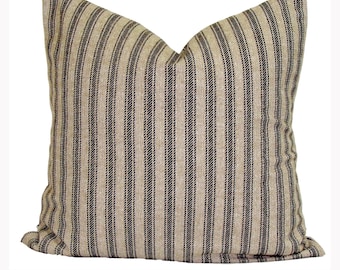 May include: Square pillow with a beige background and vertical black stripes. The pillow has a soft, textured appearance and a classic, farmhouse style. The pillow is a decorative home accent.