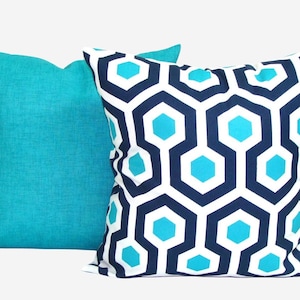 May include: Two decorative throw pillows. One is solid turquoise, the other features a geometric pattern of navy blue, white, and turquoise hexagons. The pillows are square and appear to be made of a textured fabric.