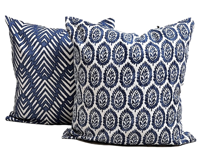 Pu&ograve; includere: Due cuscini decorativi quadrati. Uno presenta un motivo a chevron blu navy e bianco, l'altro un motivo a foglie blu navy ripetuto su sfondo bianco. I cuscini sono in tessuto e sono adatti per un divano o un letto.