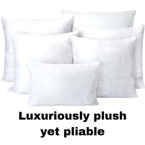 May include: A collection of white, plush pillows in various sizes. The pillows are arranged in a group, with the text "Luxuriously plush yet pliable" at the bottom. The pillows appear soft and inviting.