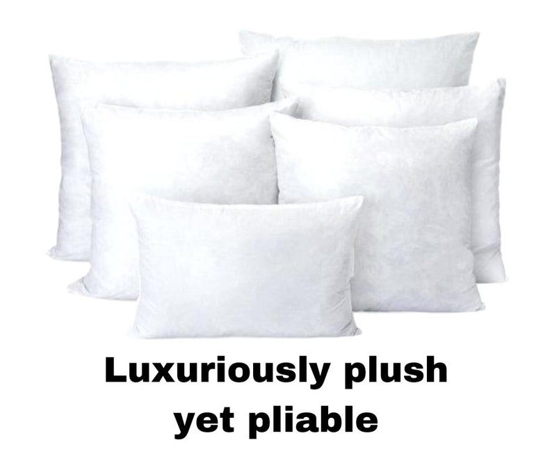 May include: A collection of white, plush pillows in various sizes. The pillows are arranged in a group, with the text "Luxuriously plush yet pliable" at the bottom. The pillows appear soft and inviting.