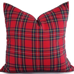May include: A red plaid pillow with a classic tartan pattern. The pillow features a bold red background with intersecting lines in black, yellow, and navy blue. This decorative pillow adds a touch of traditional style to any room.