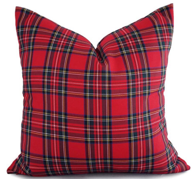 May include: A red plaid pillow with a classic tartan pattern. The pillow features a bold red background with intersecting lines in black, yellow, and navy blue. This decorative pillow adds a touch of traditional style to any room.