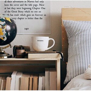 May include: A decorative globe with a black and gold design sits on a wooden nightstand next to a white mug with the word "PATIENCE" printed on it. A stack of books is visible below the nightstand.