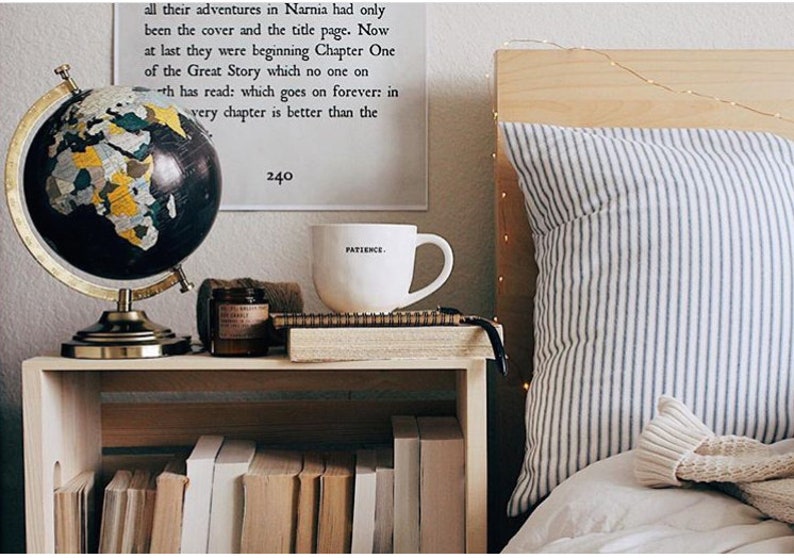 May include: A decorative globe with a black and gold design sits on a wooden nightstand next to a white mug with the word "PATIENCE" printed on it. A stack of books is visible below the nightstand.