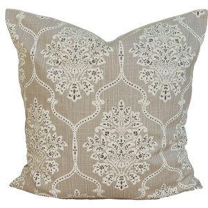 May include: A square cushion featuring a beige backdrop and a repeating white and dark brown floral design. The cushion has a textured look and a classic pattern, suitable for home decor.