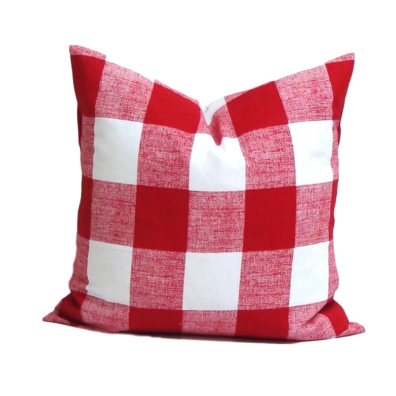 May include: A square decorative pillow with a red and white checkered pattern. The pillow has a classic gingham design, with large, evenly sized squares. The fabric appears to be a woven material, and the pillow is filled to a plump shape.
