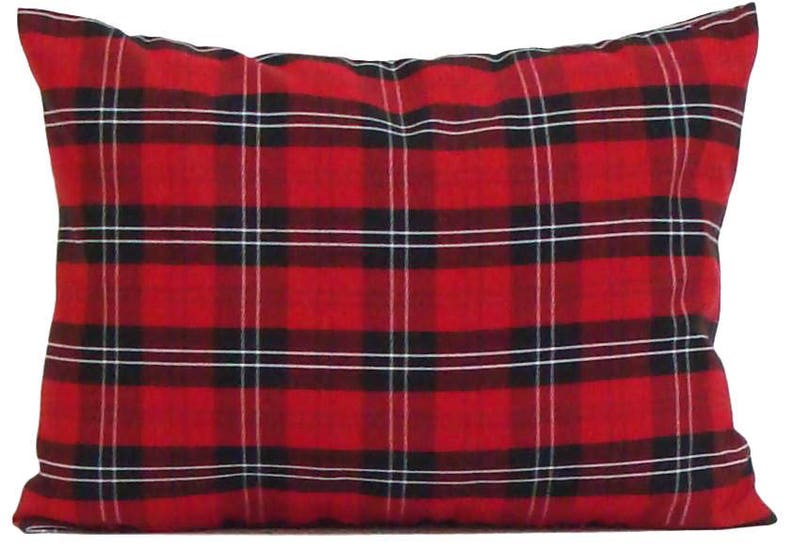 May include: A rectangular pillow with a red plaid pattern. The plaid design features thick red lines with black and white intersecting lines. The pillow is a decorative item, likely for a bed or couch.
