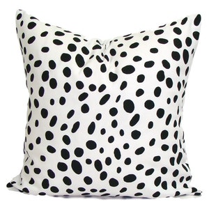 May include: Square decorative pillow with a white background and a pattern of black, irregular spots. The pillow is a solid color on the back. The pillow is a square shape.