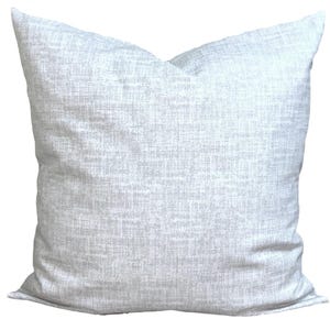 May include: A square, light grey decorative cushion with a textured fabric. The cushion has a neutral colour and a simple design, suitable for various home decor styles. The cushion is approximately 50 cm square.