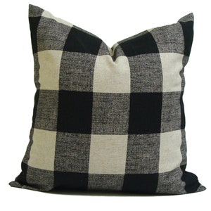 K&ouml;nnte beinhalten: Quadratisches Zierkissen mit einem schwarz-beigen B&uuml;ffelkaromuster. Das Kissen hat eine strukturierte Oberfl&auml;che und ein weiches Aussehen. Es ist f&uuml;r den dekorativen Einsatz auf einem Bett oder Sofa geeignet.