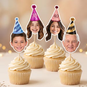 K&ouml;nnte beinhalten: Vier Cupcakes mit personalisierten Gesichtsausschnitten auf Holzst&auml;bchen. Jedes Gesicht tr&auml;gt einen Miniatur-Partyhut: blau mit 10, pink mit 30, ros&eacute;gold mit 40 und schwarz-gold mit 80. Die Cupcakes haben wei&szlig;e Glasur in Papierf&ouml;rmchen.