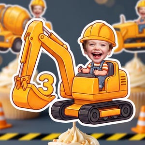 Puede incluir: Un adorno para cupcake con forma de excavadora amarilla que muestra a un niño de dibujos animados con un casco de obra amarillo en el asiento del conductor. El brazo de la excavadora muestra el número 3 en amarillo sobre un recorte blanco.