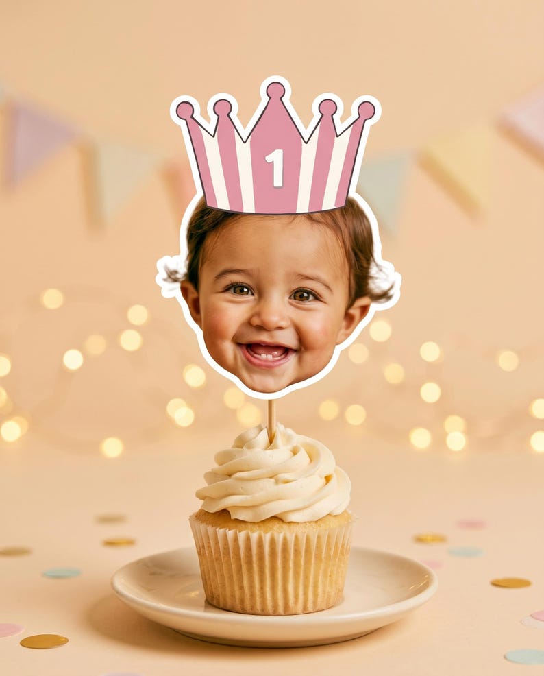 K&ouml;nnte beinhalten: Ein Cupcake-Topper mit einem Ausschnitt eines l&auml;chelnden Kindergesichts, das eine rosa-wei&szlig; gestreifte Krone mit der aufgedruckten Zahl 1 tr&auml;gt. Der Ausschnitt ist an einem d&uuml;nnen Holzstab befestigt, der in einem Cupcake steckt.
