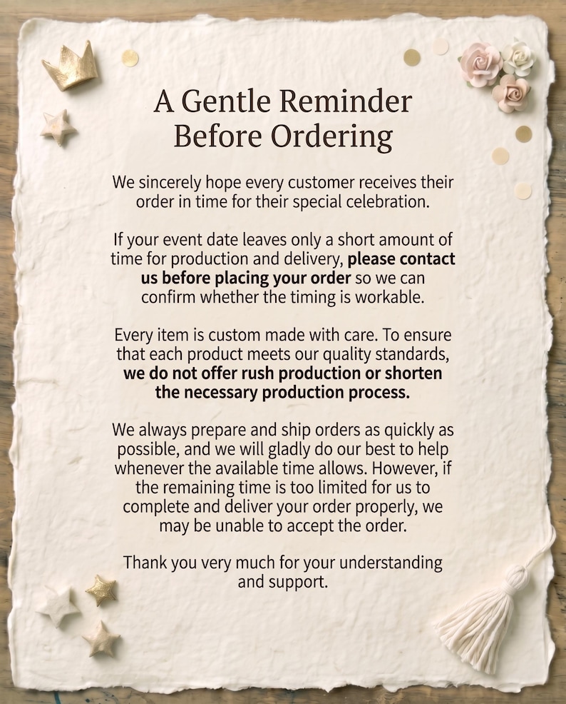 K&ouml;nnte beinhalten: Ein rechteckiges, cremefarbenes Papierschild mit unebenen R&auml;ndern und dem Text A Gentle Reminder Before Ordering, verziert mit kleinen goldenen Sternen, einer goldenen Krone sowie blassrosa und wei&szlig;en Papierblumen.