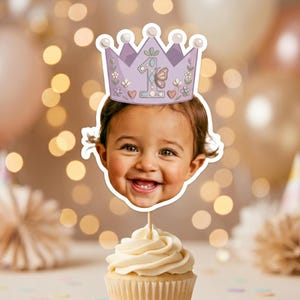K&ouml;nnte beinhalten: Ein Cupcake-Topper mit einem Ausschnitt des Gesichts eines l&auml;chelnden Kindes, das eine hellviolette Kronenillustration tr&auml;gt. Die Krone ist mit einer gro&szlig;en Zahl eins, einem Schmetterling, kleinen Blumen und Herzen verziert. Der Topper steckt auf einem St&auml;bchen in einem Vanille-Cupcake.