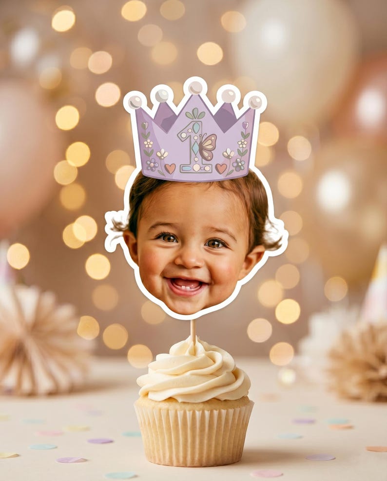 K&ouml;nnte beinhalten: Ein Cupcake-Topper mit einem Ausschnitt des Gesichts eines l&auml;chelnden Kindes, das eine hellviolette Kronenillustration tr&auml;gt. Die Krone ist mit einer gro&szlig;en Zahl eins, einem Schmetterling, kleinen Blumen und Herzen verziert. Der Topper steckt auf einem St&auml;bchen in einem Vanille-Cupcake.