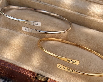 Peut inclure: Deux bracelets ouverts, l'un argenté et l'autre doré, avec des gravures personnalisées. Le bracelet argenté porte les inscriptions ELLA et R + E, tandis que le bracelet doré porte les inscriptions HENRY et 02.14.2024 sur les extrémités.