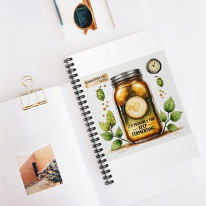 May include: A spiral-bound notebook featuring a jar illustration with the text "IT'S PROBABLY FINE - KEEP FERMENTING." The notebook also includes a clock, hops, and the words "Fermentation Log". The design is in full colour.