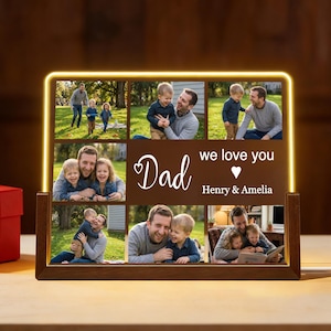 May include: A wooden photo display with a warm yellow LED border. The display features multiple family photos and the words "Dad, we love you" with a heart and names. A thoughtful gift.