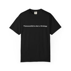 Op de afbeelding: Zwart t-shirt met de witte tekst "Password123 is Not a Strategy" over de borst. Het shirt met korte mouwen heeft een ronde hals en een label in de nek. Het shirt is gemaakt van een zacht materiaal.