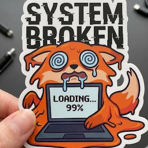 Pode incluir: Um adesivo com o texto "SYSTEM BROKEN" acima de uma raposa de desenho animado laranja com olhos em espiral e um laptop exibindo "LOADING... 99%". A raposa tem detalhes azuis e brancos.