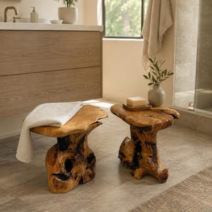 May include: Two natural wood stools with organic, irregular shapes and dark, charred-looking knots. One stool features a white folded towel draped over its top, while the other holds a small wooden tray with a bar of soap and a small vase.