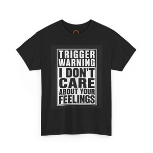 May include: A black short-sleeved t-shirt featuring a white rectangular graphic on the chest. The text inside the graphic reads: TRIGGER WARNING I DON'T CARE ABOUT YOUR FEELINGS. The shirt has a crew neckline and a standard fit design.