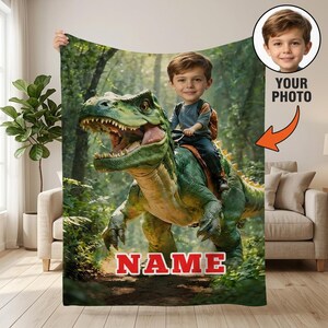 May include: A green and yellow dinosaur with a boy riding on its back is featured on a blanket. The blanket has a forest background. The word "NAME" is printed in red at the bottom. A photo of a boy is in the upper right corner.