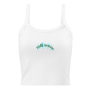 May include: A white sleeveless crop top featuring a central graphic design. The text "roll wave" is printed in dark green letters, arched over a cluster of light blue stars of varying sizes, centered on the chest of the garment.