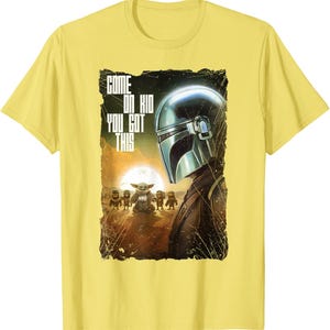 Op de afbeelding: Geel T-shirt met een afbeelding uit de Star Wars-serie. Het ontwerp bevat de Mandalorian helm, Grogu en andere personages met de tekst "COME ON KID YOU GOT THIS".