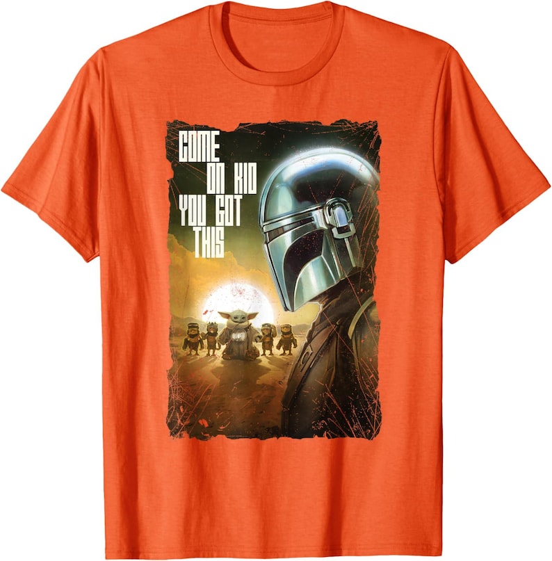 Op de afbeelding: Oranje t-shirt met een afbeelding uit de Star Wars-serie. Het ontwerp toont de helm van de Mandalorian, Grogu en andere personages, met de tekst "COME ON KID YOU GOT THIS".