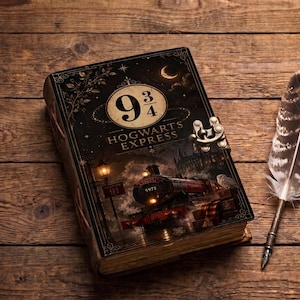 Puede incluir: Un diario rectangular con una cubierta oscura que muestra una locomotora de vapor, el texto 9 3/4 y HOGWARTS EXPRESS, y un cierre de pestillo metálico. Junto al diario hay una pluma larga con patrón marrón y blanco y una punta de metal plateado.