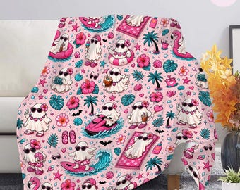 May include: A soft throw blanket featuring a repeating pattern of white ghosts on a light pink background. The ghosts are depicted in various summer vacation activities, including surfing, swimming in pink floats, and relaxing with tropical drinks.