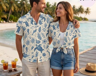 May include: A short-sleeved button-down shirt and a matching tie-front blouse, both featuring a blue marine-themed print of sea turtles, seahorses, shells, and coral on a cream background. The shirt is paired with beige shorts and the blouse with denim shorts.