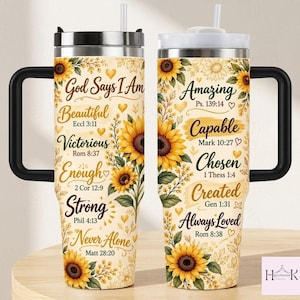 May include: Two stainless steel tumblers with black handles and lids, featuring a cream background with yellow sunflower illustrations, small gold hearts, and inspirational text including God Says I Am Beautiful, Victorious, Enough, Strong, Never Alone, Amazing, Capable, Chosen, Created, and Always Loved.