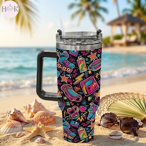 May include: A stainless steel tumbler with a black handle and a clear lid featuring a white straw. The exterior has a black background with a colorful 1980s-inspired pattern of roller skates, handheld game consoles, headphones, and lightning bolts.