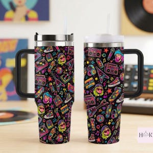 May include: Two stainless steel tumblers with handles and straws, featuring a black background covered in a colorful 1980s-themed pattern of boomboxes, cassette tapes, electric guitars, sneakers, disco balls, and stylized faces with bubblegum.