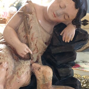 May include: A vintage figurine of a sleeping girl with a lamb. The girl is wearing a white dress and has long brown hair. The lamb is brown and white and is lying next to the girl.