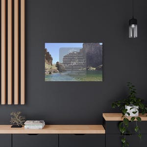 Könnte beinhalten: Ein Leinwanddruck mit einer malerischen Landschaft mit Wasser und Felsformationen. Das Bild hat eine transparente Überlagerung mit dem Wort "Wanderlust" und anderem Text. Der Druck wird an einer dunklen Wand angezeigt.