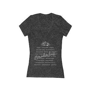 Könnte beinhalten: Dunkelgraues V-Ausschnitt-T-Shirt mit weißem Text und einer Berg-Grafik. Der Text enthält Sätze wie "Frei, Erkunden, Roam, Abenteuer, Entdeckung, Freiheit, Offene Straßen, Neue Horizonte, Wanderlust, Werden, Fern, Unbekannt, Möglichkeit, Wach."