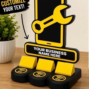 May include: A black and yellow display stand featuring a smartphone icon with a wrench overlay, a rectangular sign with the text YOUR BUSINESS NAME HERE, and three circular NFC logos on the base. The text CUSTOMIZE YOUR TEXT is visible.