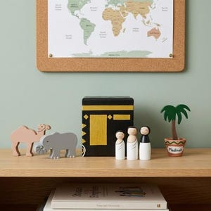 Può includere: Scaffale in legno con oggetti decorativi: cammello, elefante, cubo nero con dettagli dorati, tre bambole di legno e una palma in vaso. Una mappa del mondo è appesa al muro sopra.