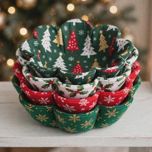 Peut inclure: Un ensemble de trois bols en tissu imbriqués avec un design à bords festonnés. Le bol intérieur présente un fond vert foncé avec des sapins de Noël rouges, blancs et dorés. Le bol intermédiaire a un fond blanc avec du houx. Le bol extérieur est vert foncé avec des flocons dorés, et la couche intermédiaire est rouge avec des flocons blancs.