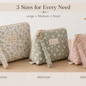 May include: Three zippered pouches in large, medium, and small sizes, featuring floral patterns in cream, sage green, and soft pink. Each pouch includes a matching wrist strap, a gold-tone zipper, and a rectangular label with the text Handmade.